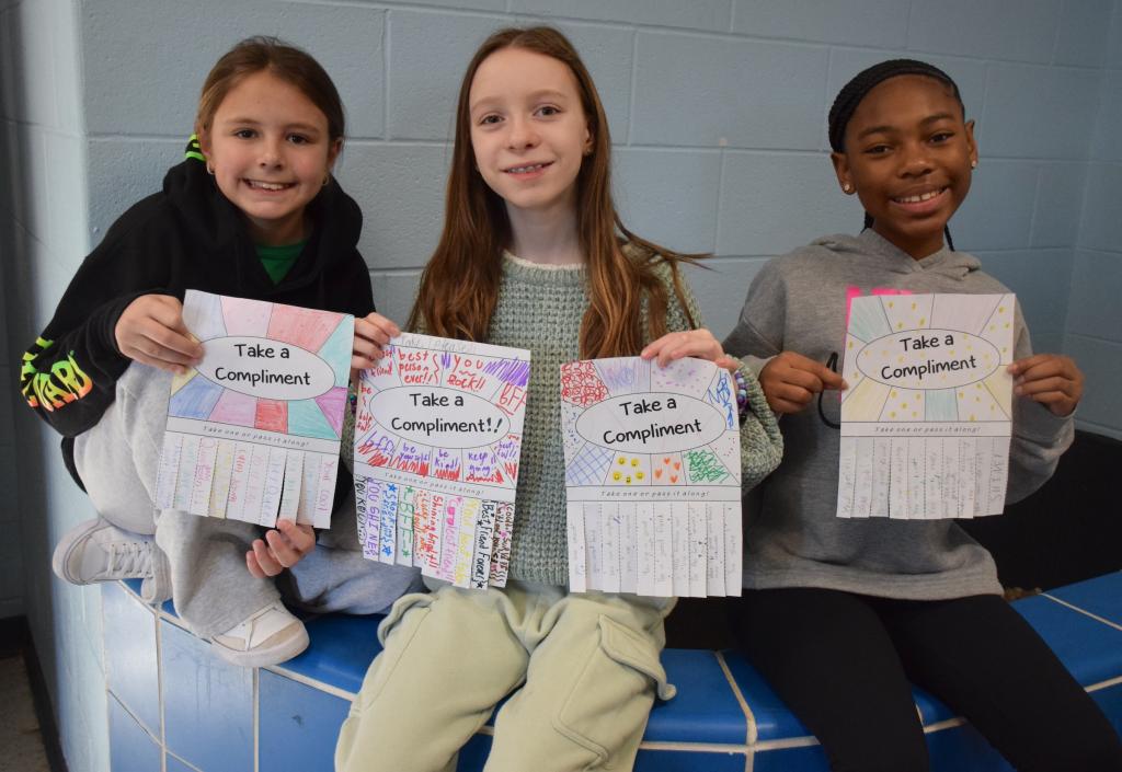 three girls holding colorful signs
